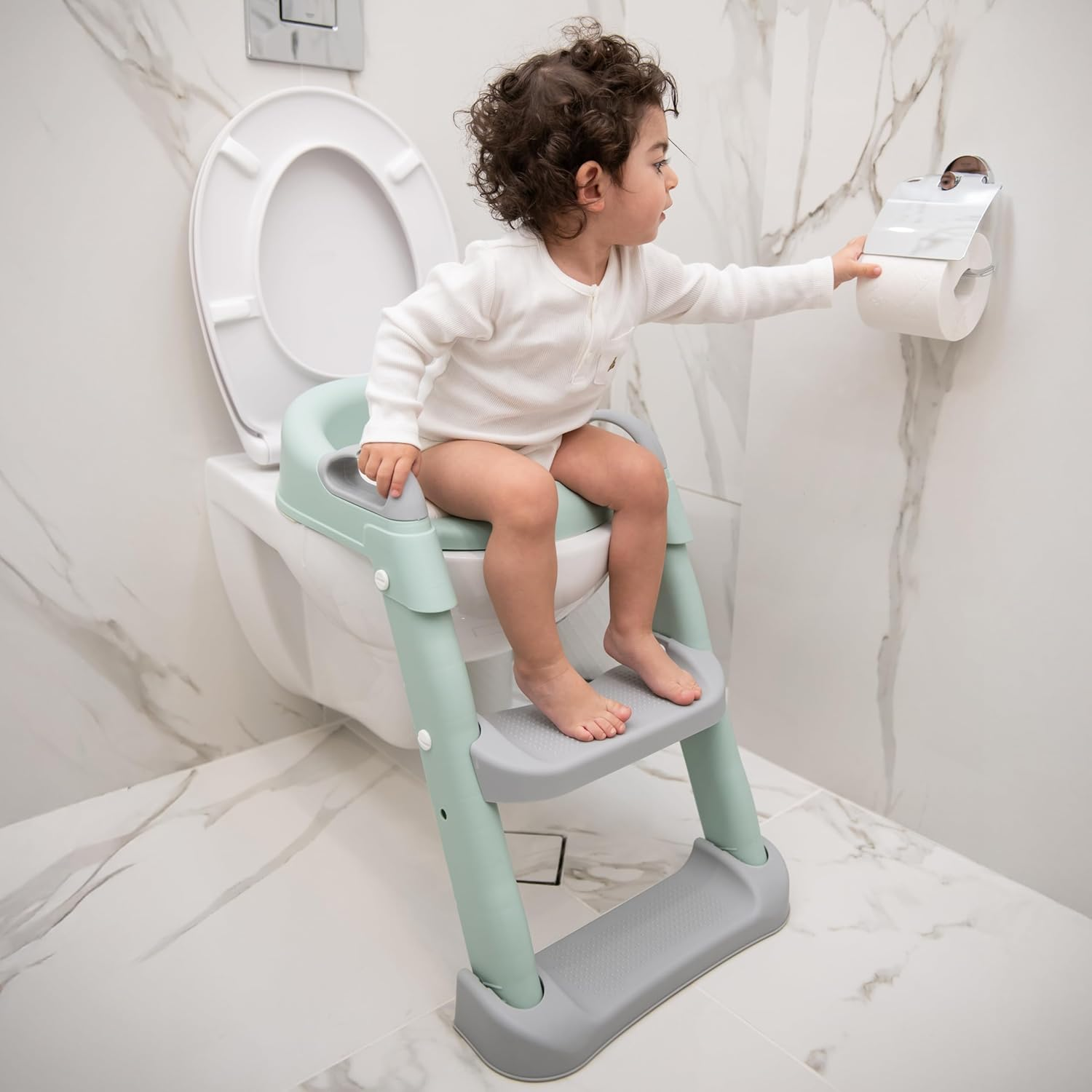 Kleines Kind auf einer Toilettenleiter, das nach Toilettenpapier greift.