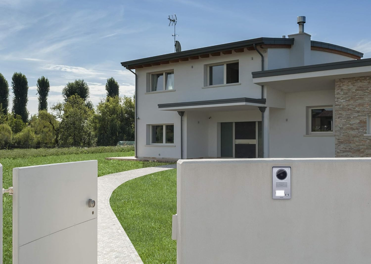 Una casa moderna bianca con cancello d'ingresso e sentiero lastricato.