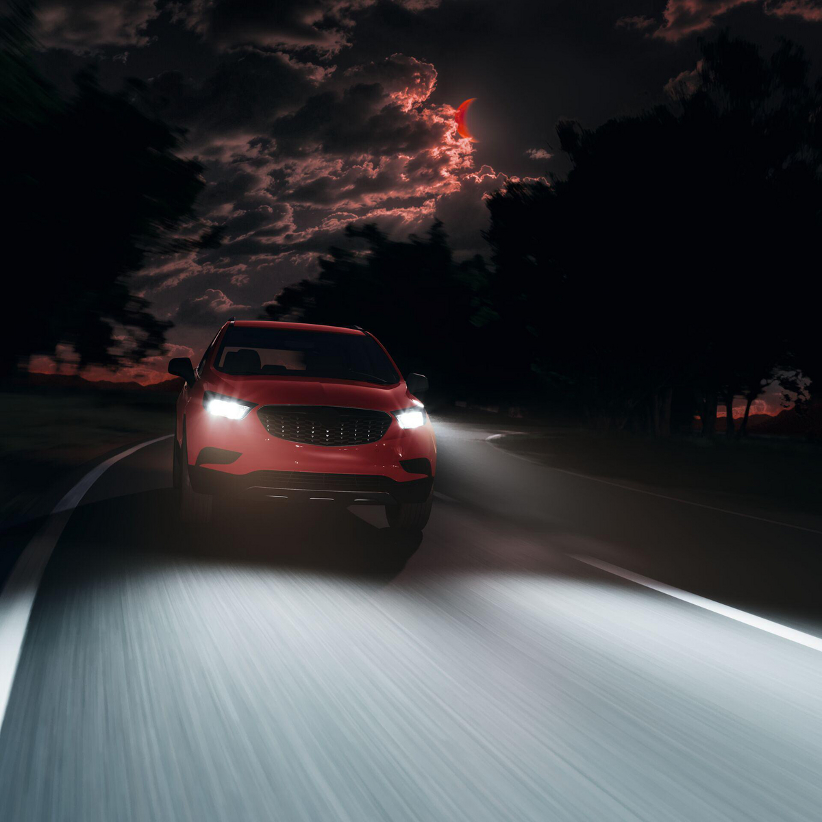 Ein rotes Auto fährt nachts auf einer dunklen Straße, der Mond ist am Himmel.
