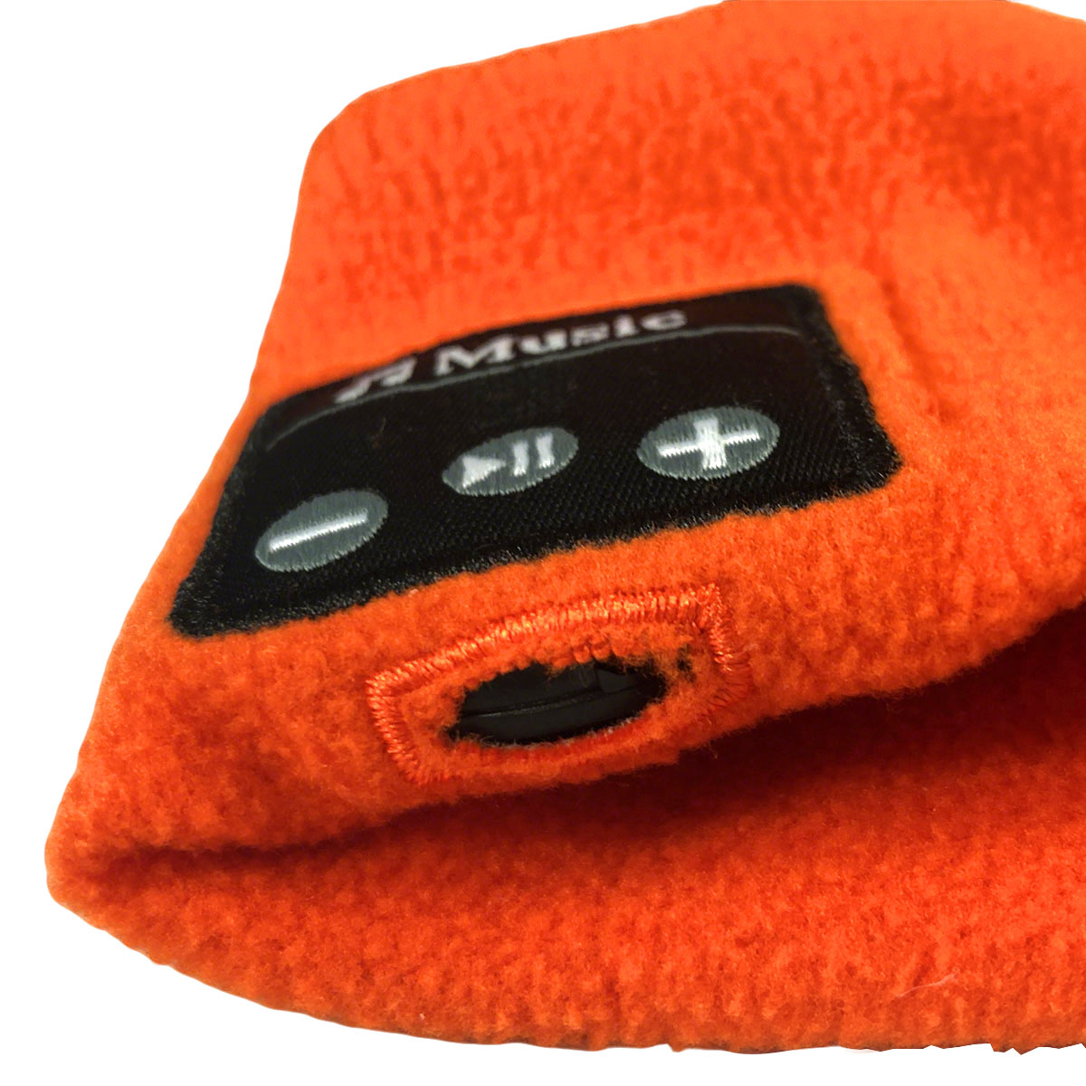 Nahaufnahme einer orangefarbenen Fleece-Mütze mit schwarzem Aufnäher für Musiksteuerung und Ladeanschluss.