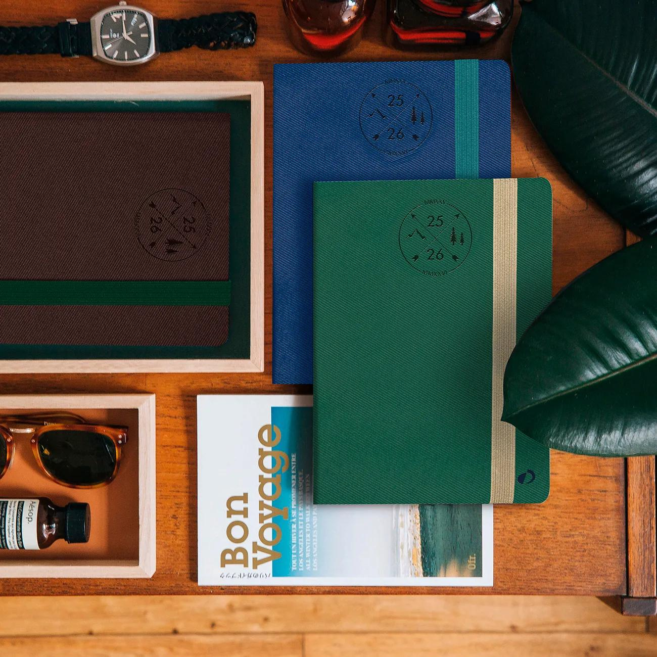 Una mesa con cuadernos, un reloj, gafas de sol, perfume y una revista.
