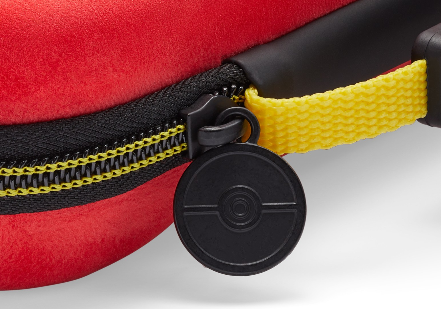 Czerwone etui z czarnym zamkiem, żółtą taśmą i zawieszką Poké Ball.