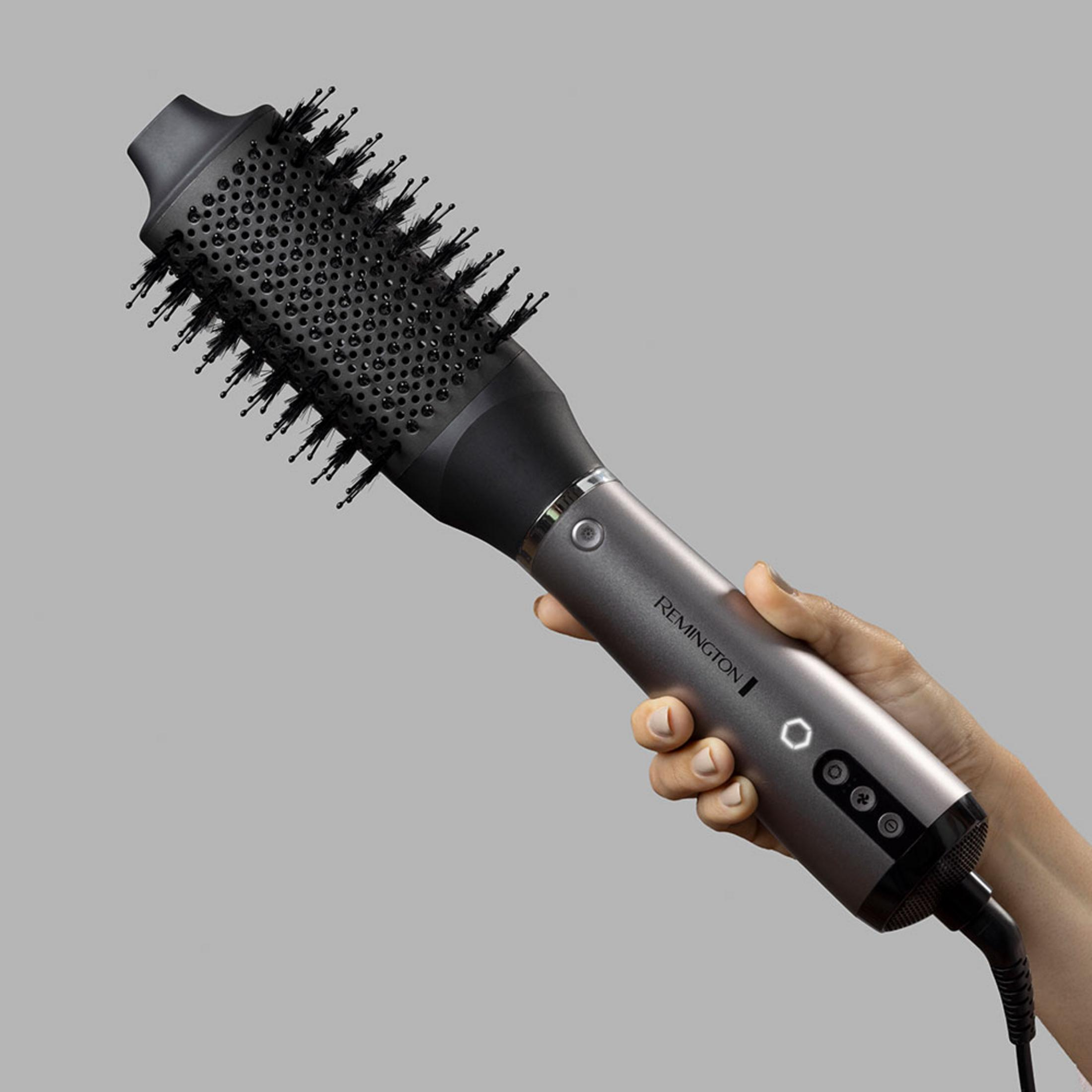 Una mano tiene un asciugacapelli Remington grigio con testina a spazzola nera.