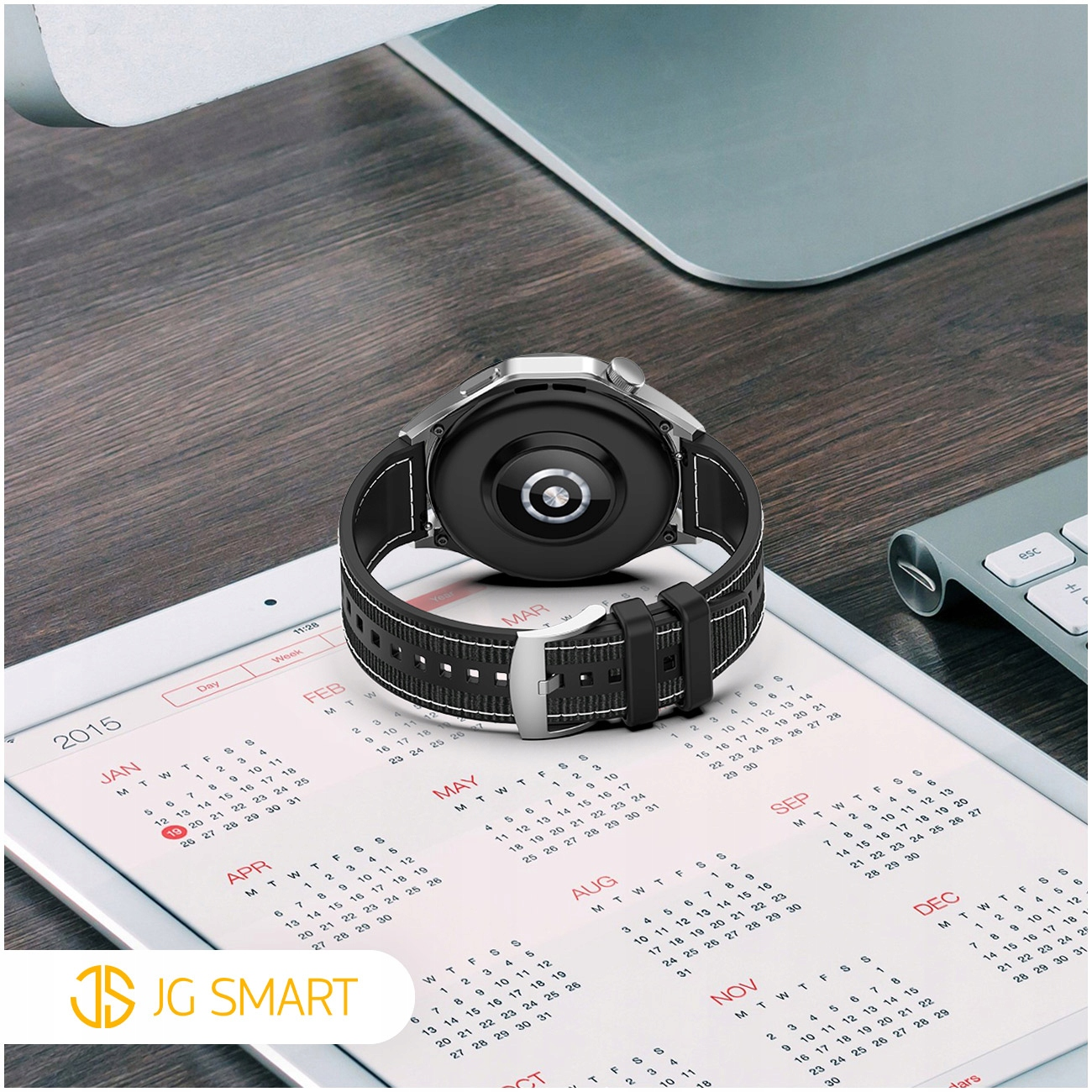 Czarny smartwatch leży na tablecie z kalendarzem na rok 2015.