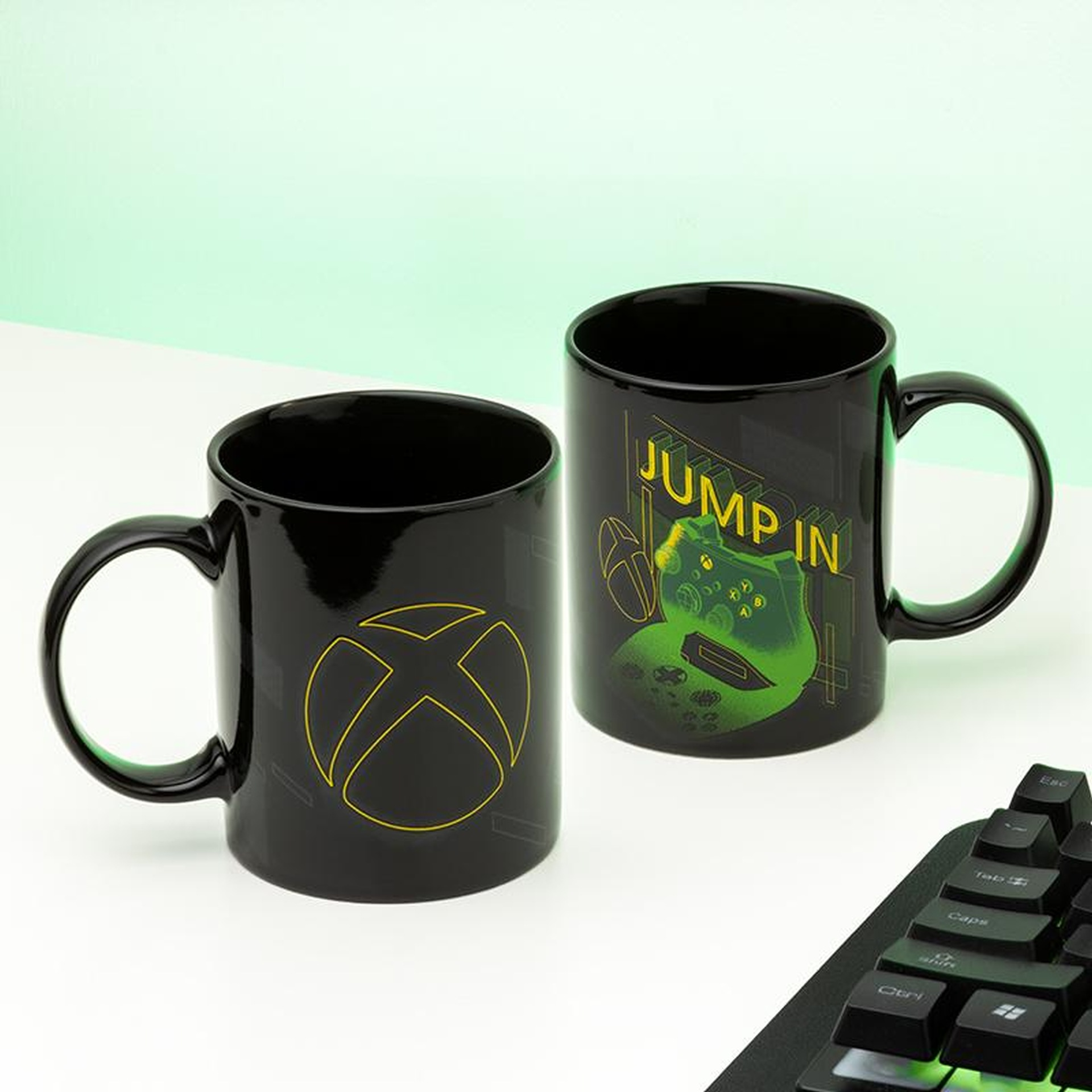 Dwa czarne kubki z logo Xbox i wzorem kontrolera.