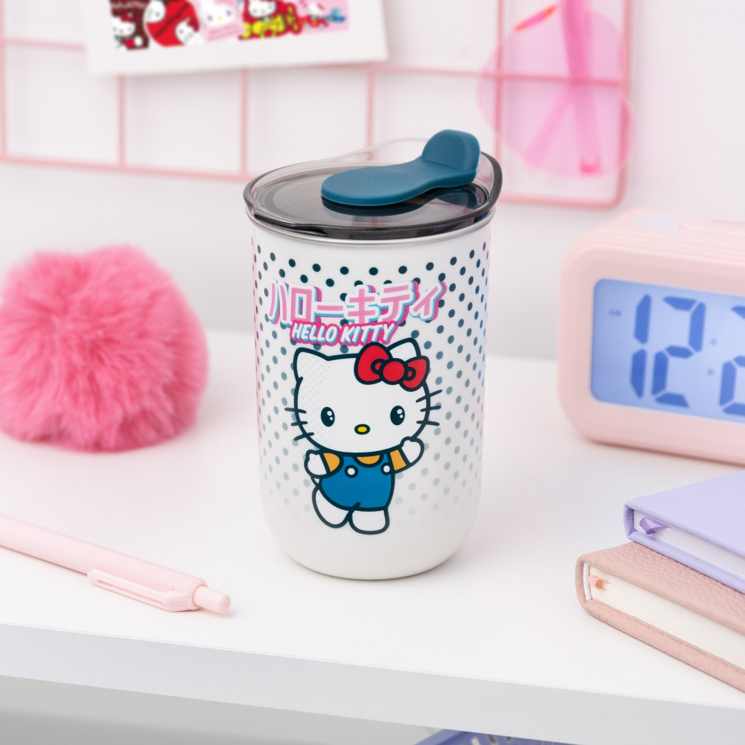 Kubek Hello Kitty w kropki, obok różowy pompon i długopis.
