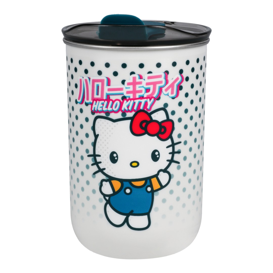 Biały kubek Hello Kitty w niebieskim ogrodniczku i czerwonej kokardce, na tle w kropki.