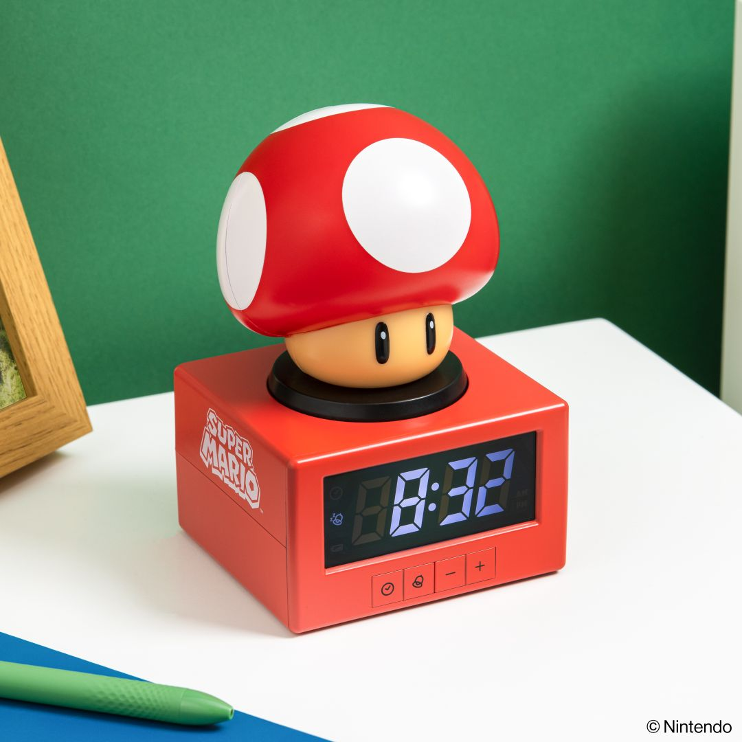 Czerwony budzik w kształcie grzyba Super Mario stoi na białym stole.