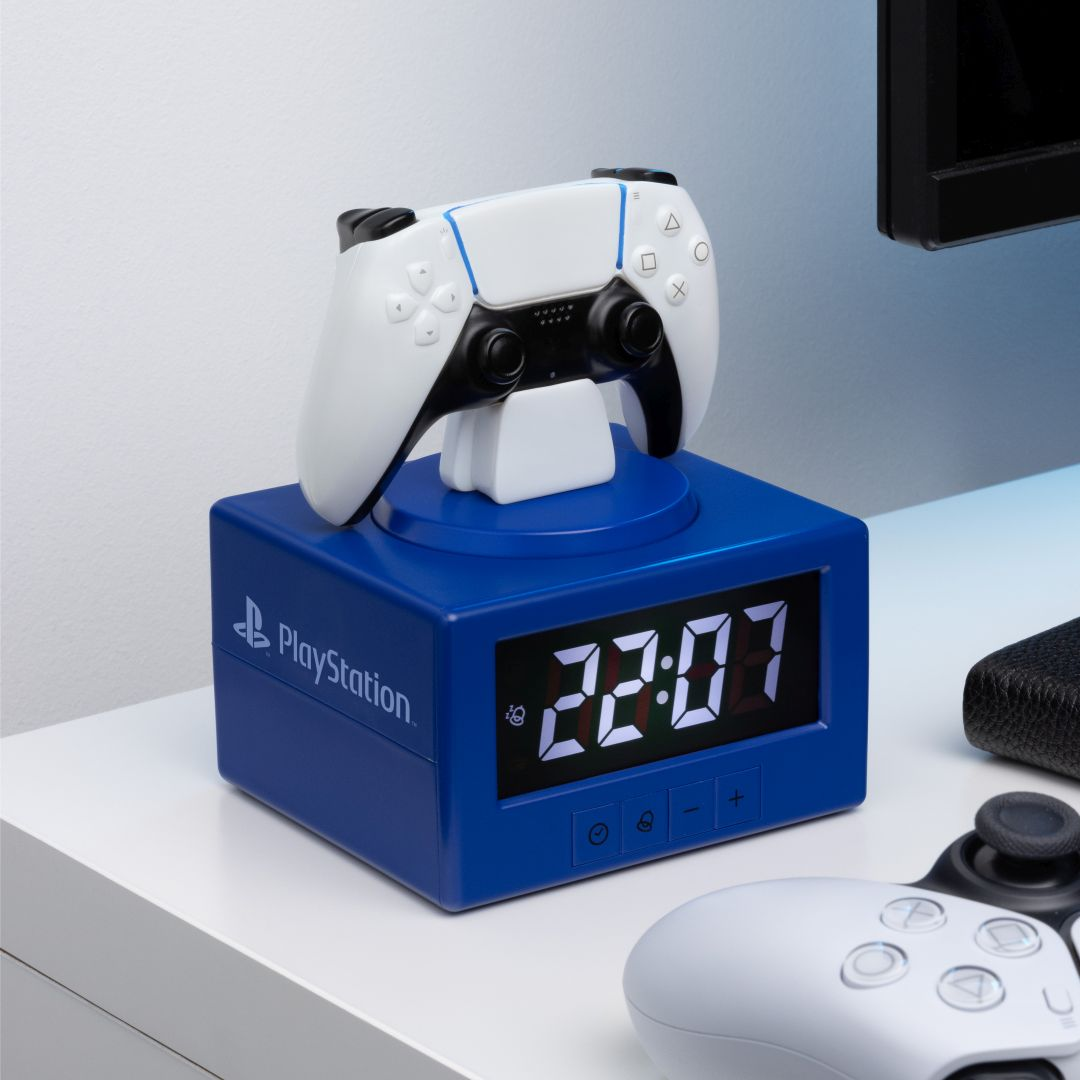 Niebieski budzik PlayStation z białym kontrolerem na górze. Godzina 22:07.
