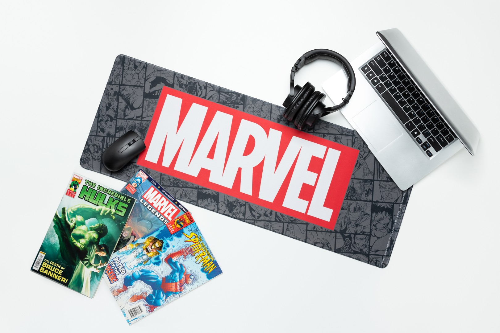 Podkładka pod mysz Marvel z komiksami, laptopem, myszą i słuchawkami na białym tle.