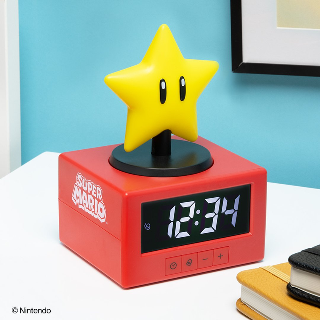 Czerwony budzik Super Mario z żółtą gwiazdą na górze. Pokazuje godzinę 12:34.