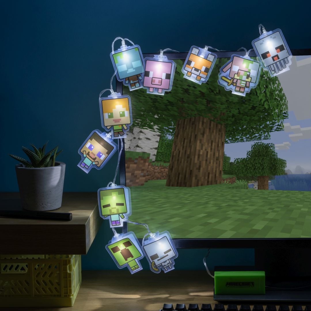 Światełka z postaciami Minecraft na biurku przed ekranem komputera.