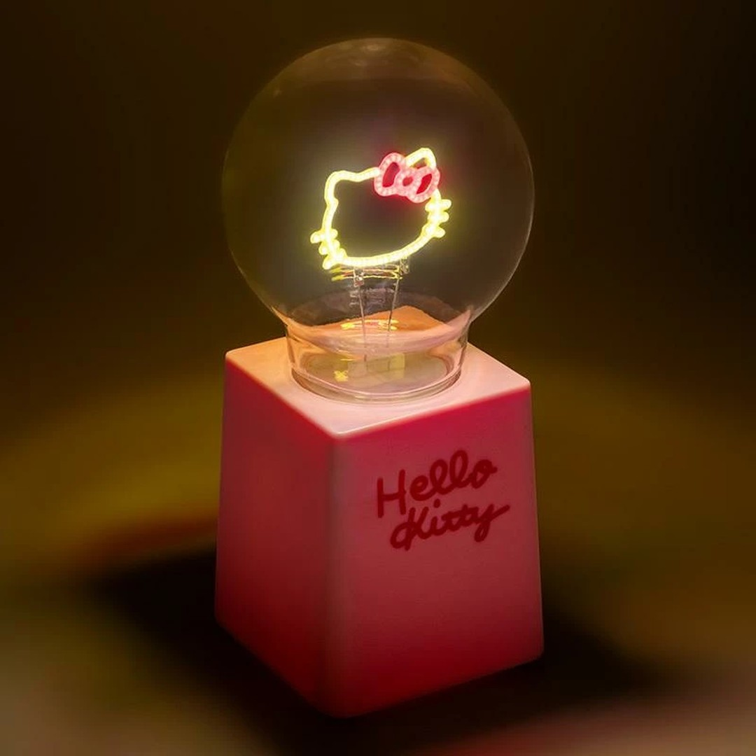 Neonowe światło w kształcie Hello Kitty świeci w przezroczystej żarówce, na różowej podstawie.