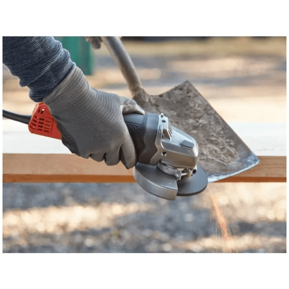 Hand mit Handschuh benutzt Winkelschleifer an Holz, Funken fliegen.