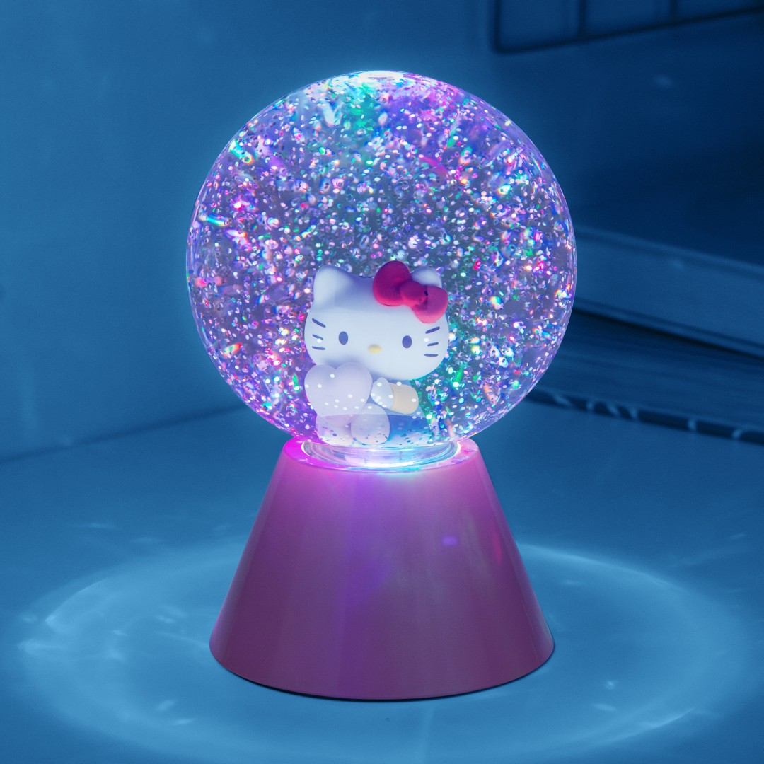 Hello Kitty w kuli śnieżnej z brokatem, różową podstawą i niebieskim światłem.