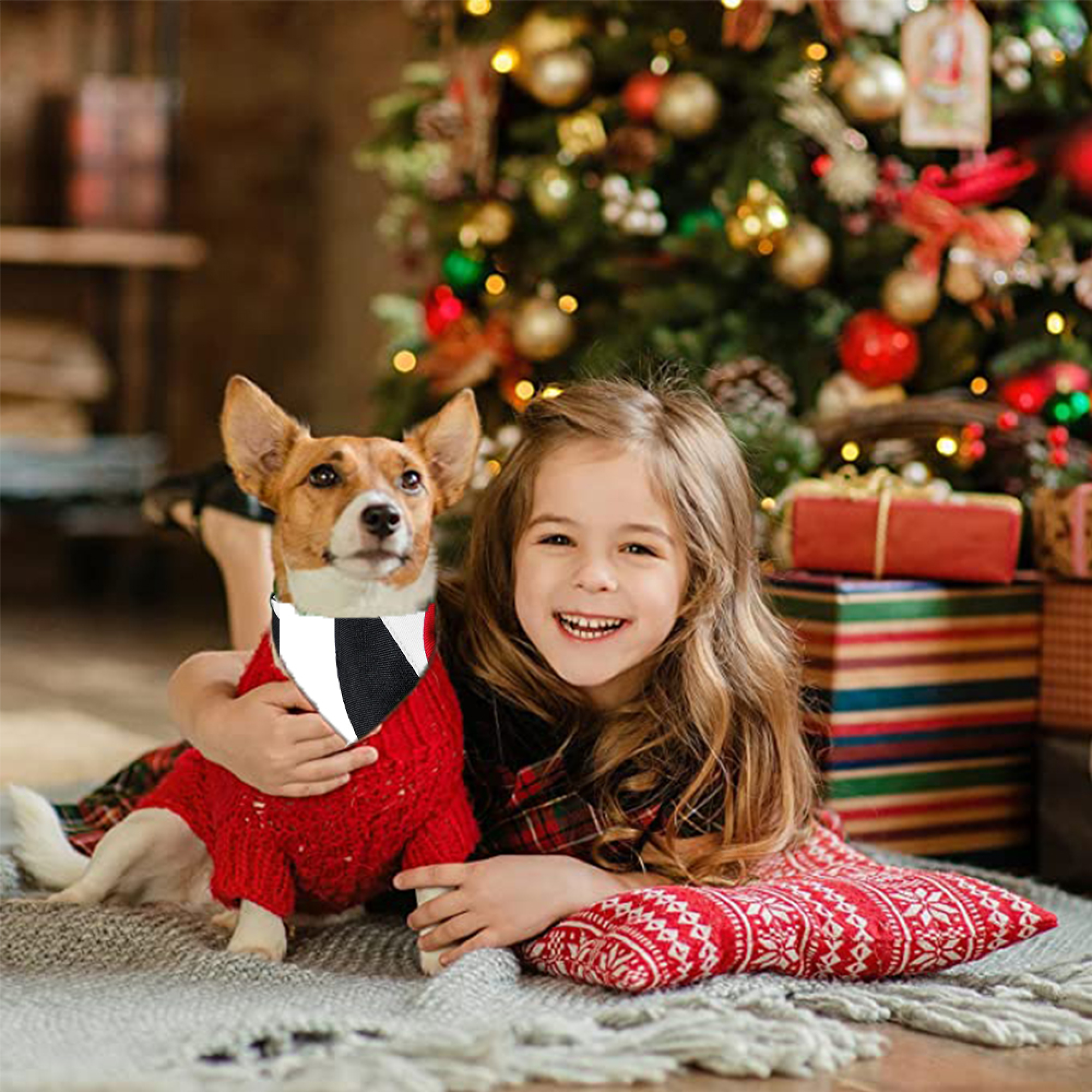 Ein Mädchen und ein Hund liegen vor einem Weihnachtsbaum mit Geschenken.