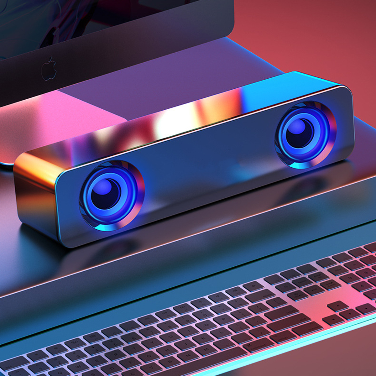 Ein schlanker, metallischer Lautsprecher mit blauen Lichtern, neben einem Computer und einer Tastatur.