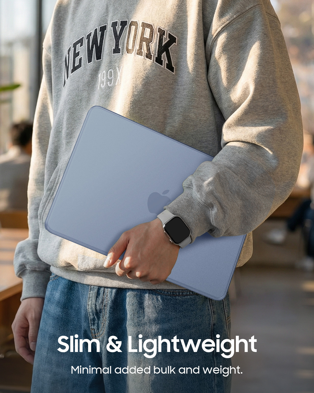 Person in grauem Sweatshirt mit "New York"-Aufdruck hält einen blauen Laptop.