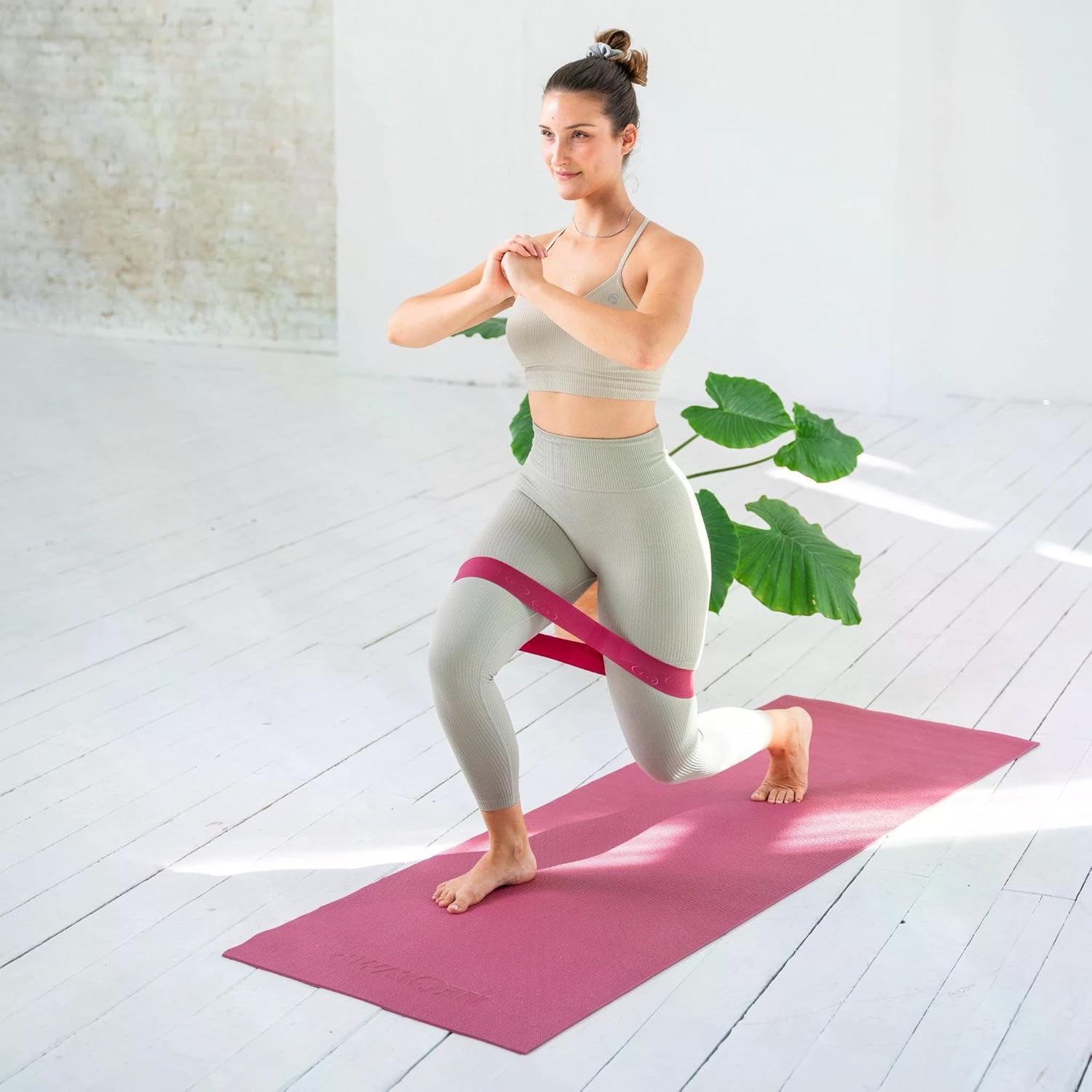 Frau macht Ausfallschritte mit Widerstandsband auf einer Yogamatte.