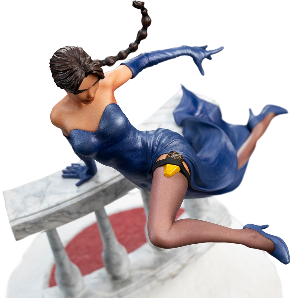 Eine Frau in einem blauen Kleid und Handschuhen, die sich an einer Marmorbalustrade festhält.
