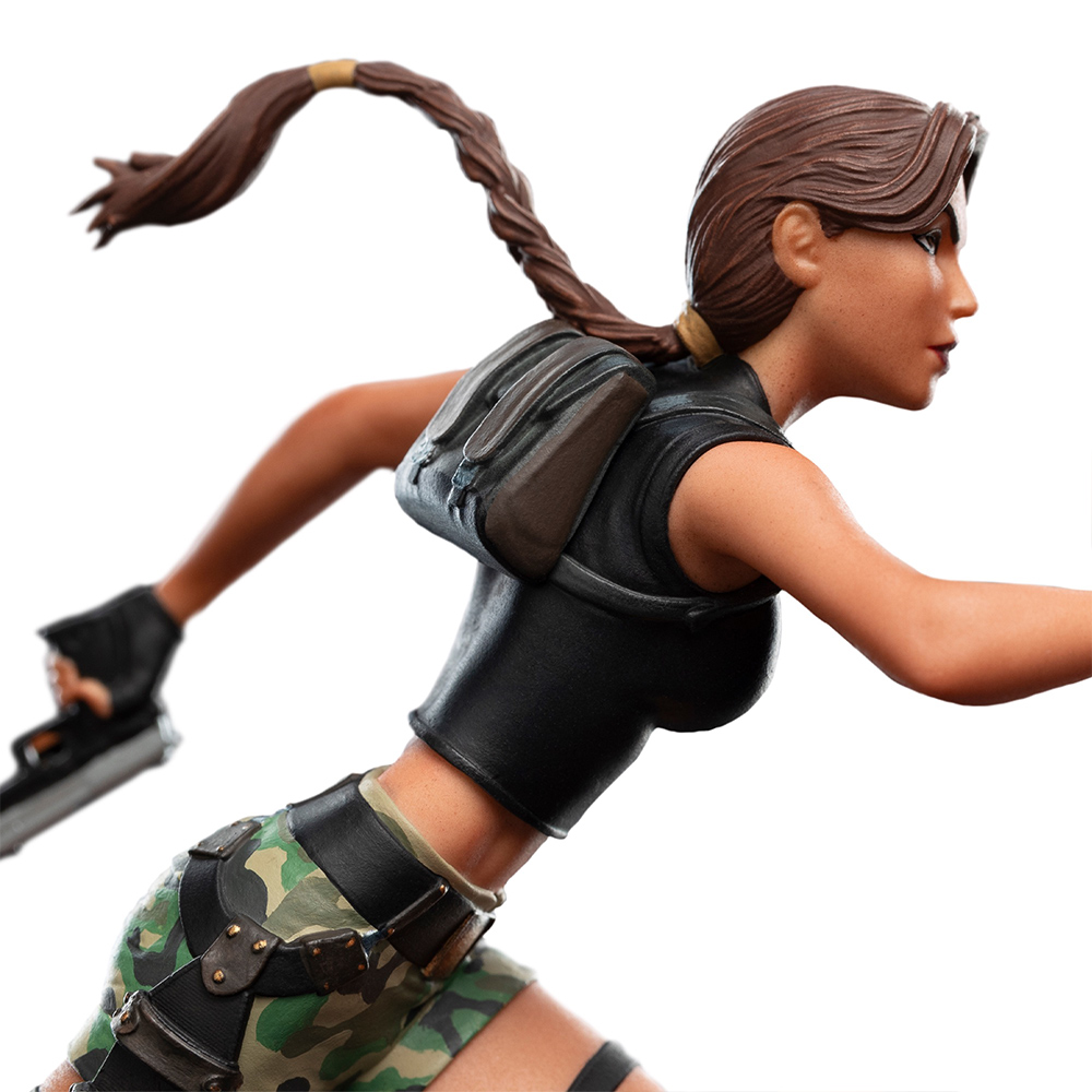 Eine Figur von Lara Croft in Tarnshorts und schwarzem Top, mit Waffe und Rucksack.