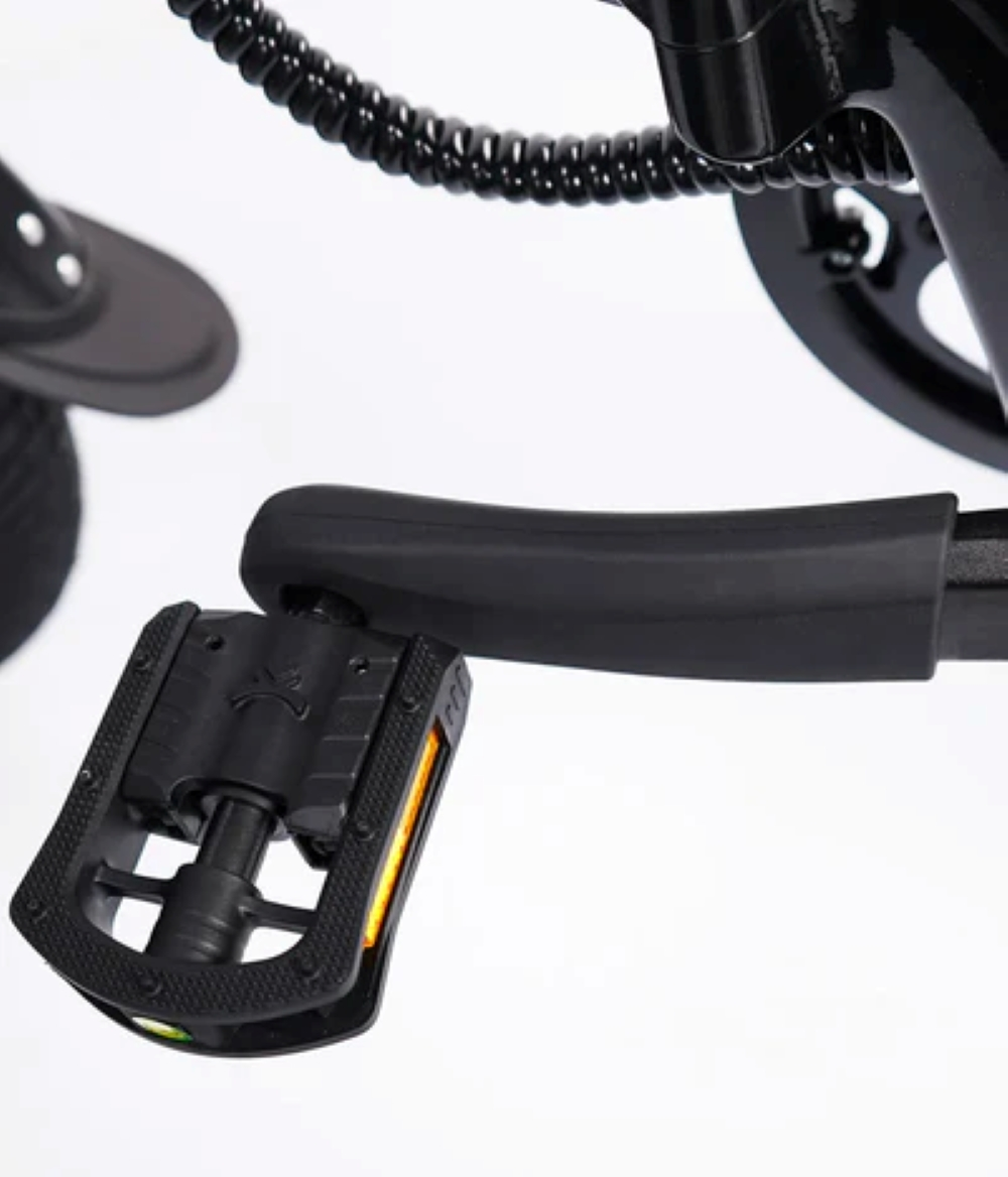 Pedale bicicletta nero con riflettore, primo piano di una parte di bicicletta.