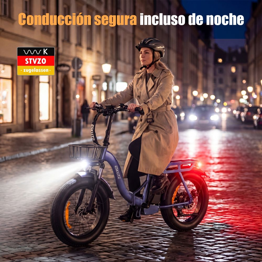 Mujer anda en e-bike por calle empedrada de noche, luces encendidas.