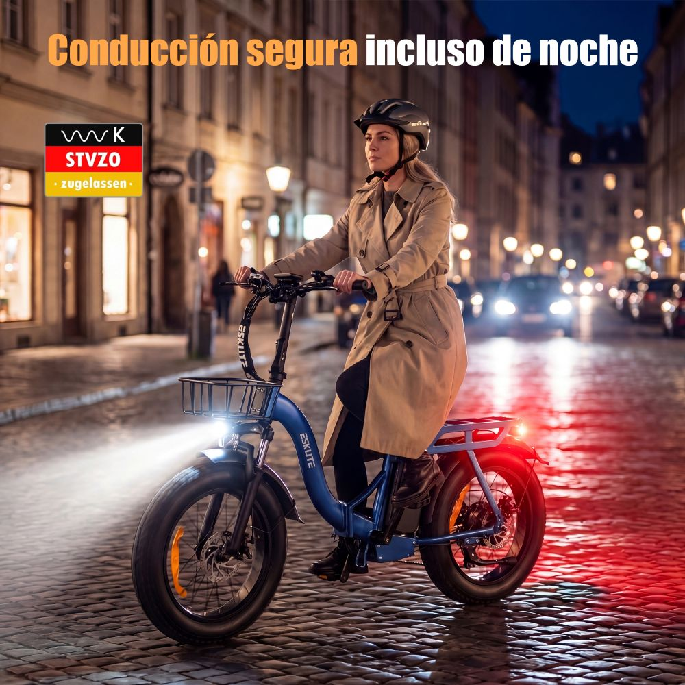 Una mujer monta una e-bike azul por la noche en una calle adoquinada.