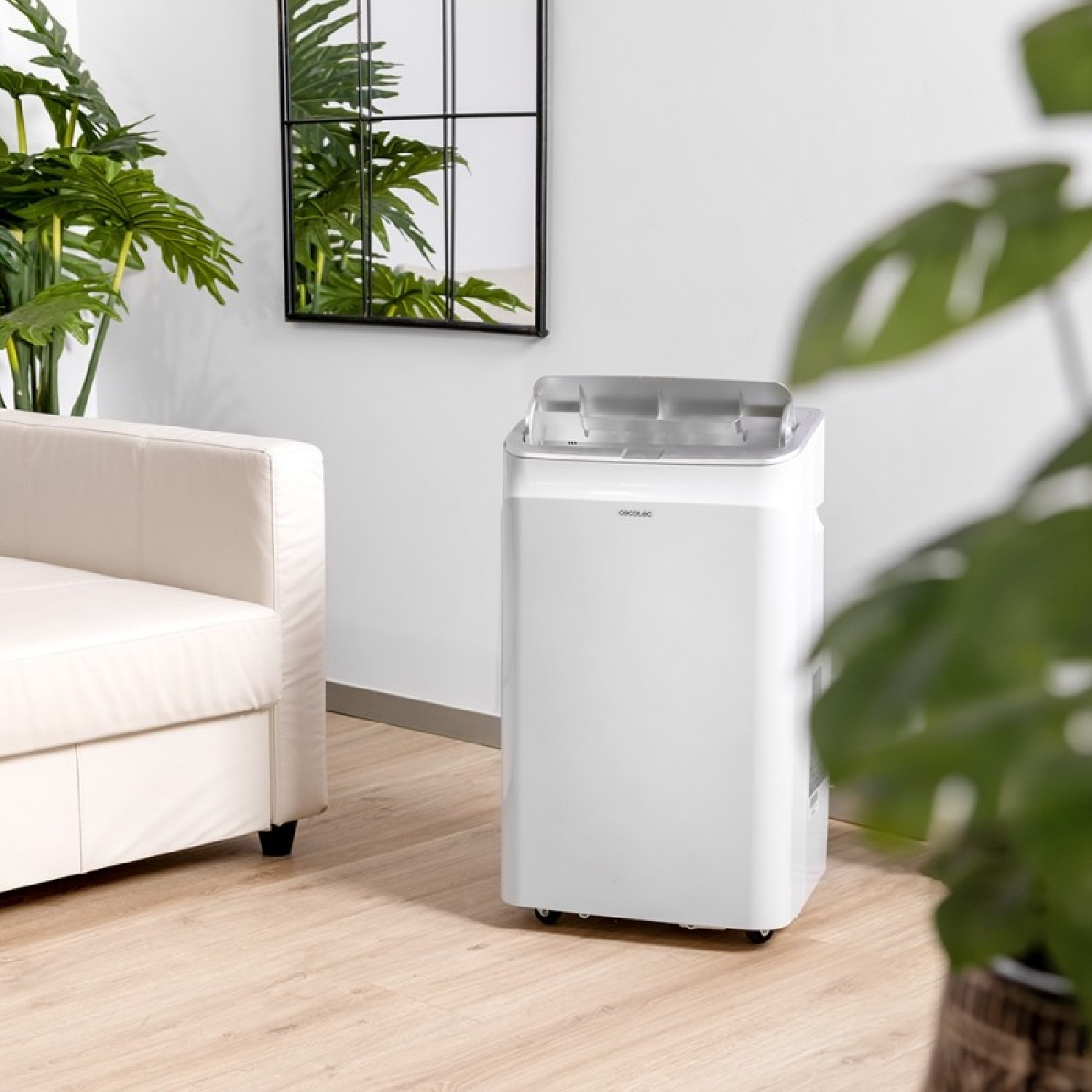 Un refrigeratore d'aria bianco accanto a un divano beige con piante.