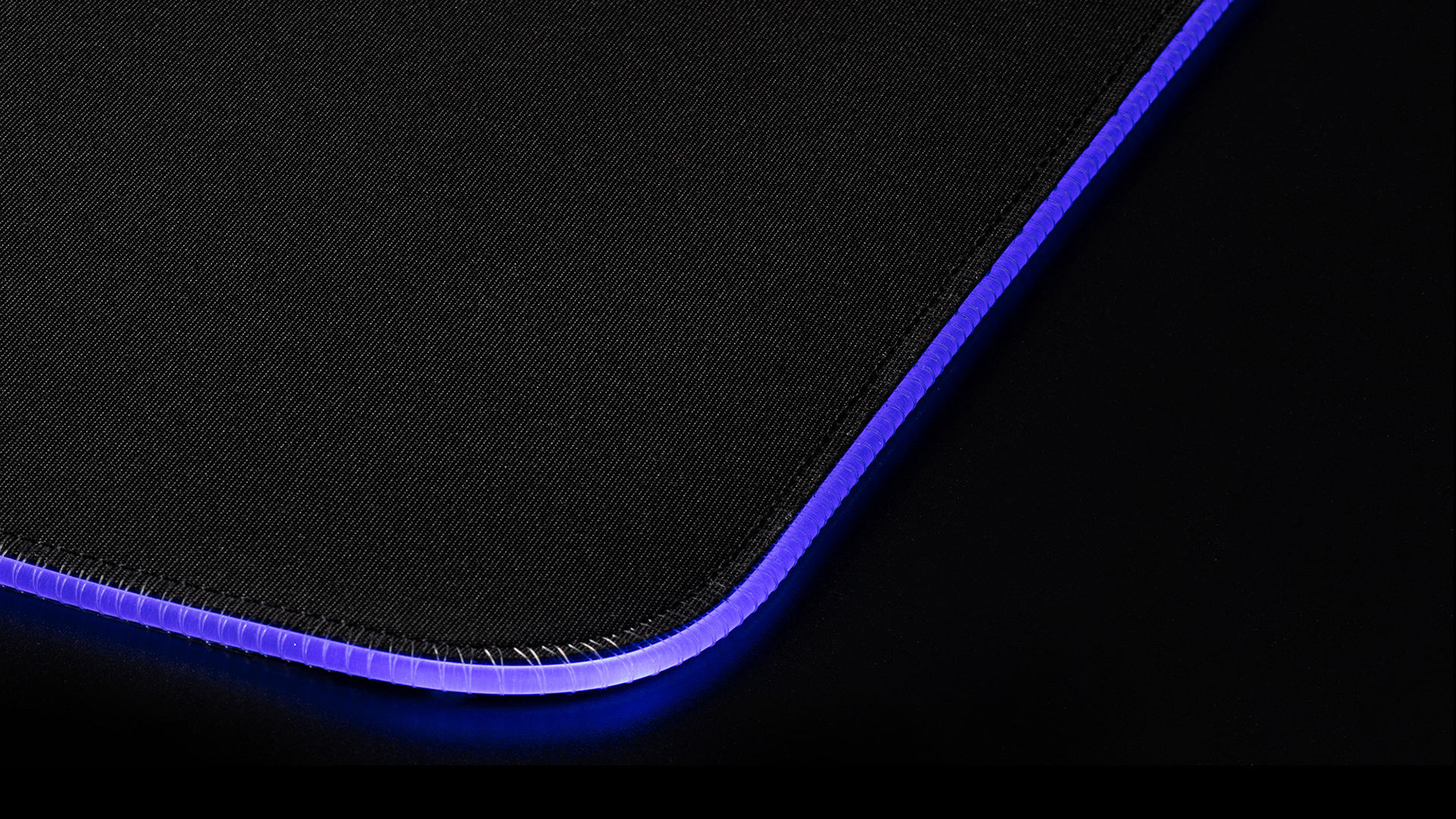 Tapis de souris noir avec bordure bleue illuminée. Gros plan.