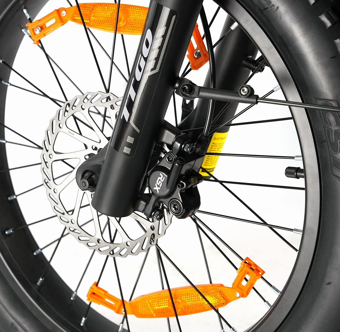 Primo piano di una ruota anteriore di bicicletta nera, freno a disco e forcella ammortizzata.