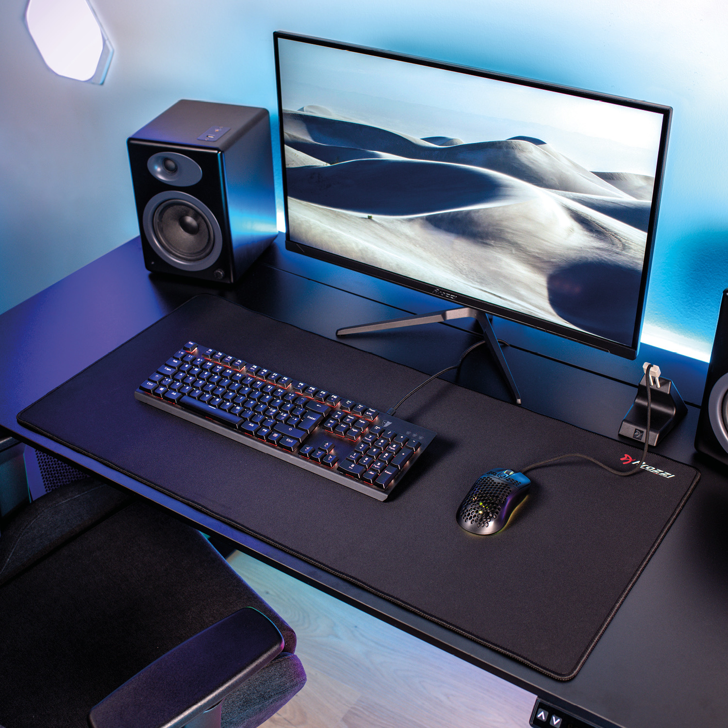 Una postazione da gaming con monitor, tastiera, mouse e altoparlanti su una scrivania nera.