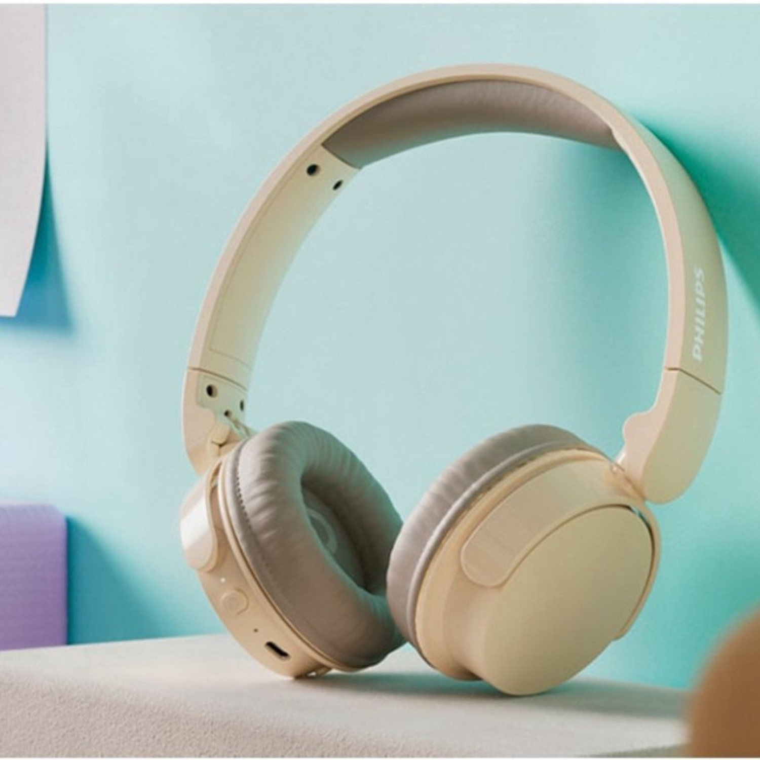 Auriculares Philips beige con almohadillas descansan sobre una superficie clara.