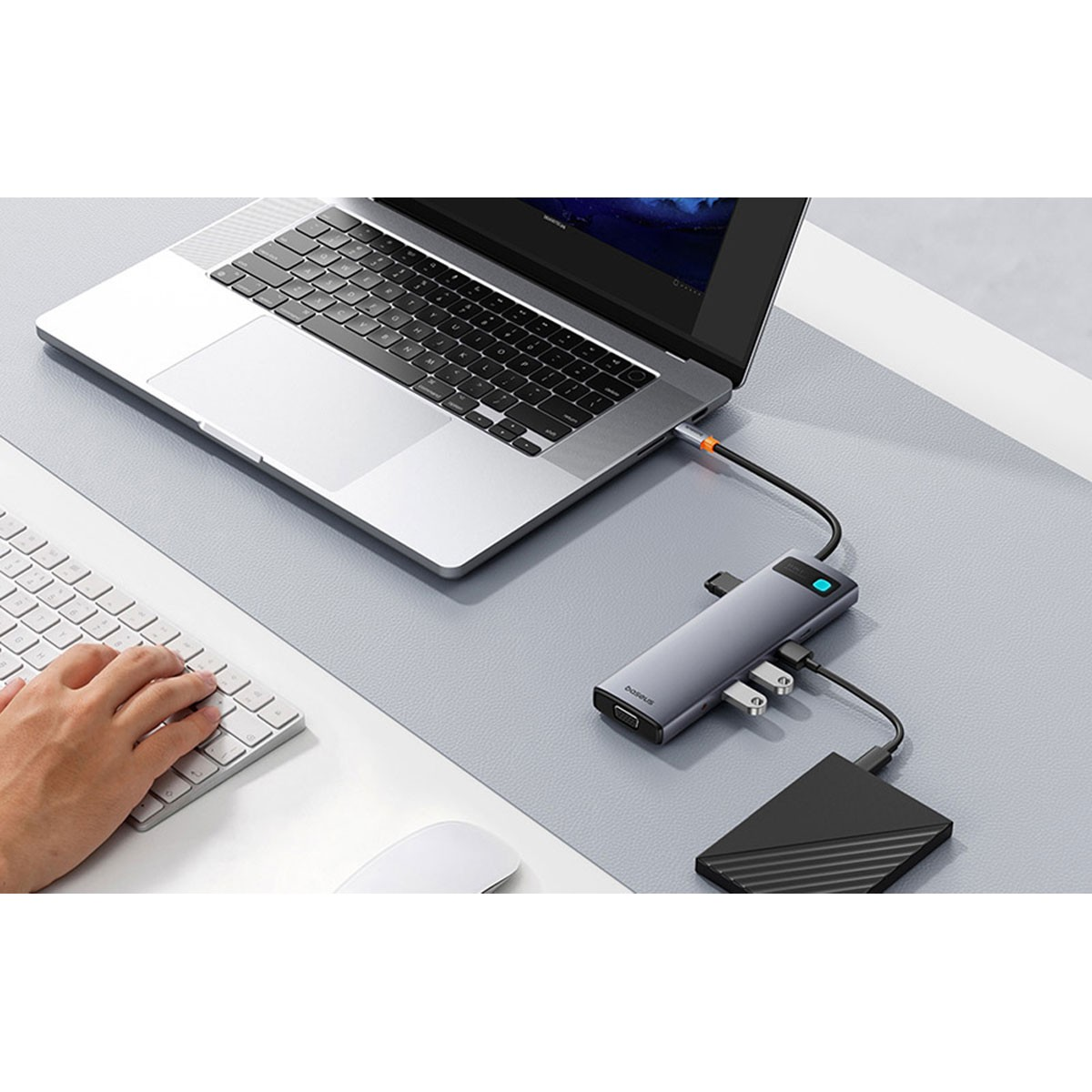 Un hub USB-C grigio collega laptop, tastiera, mouse e disco rigido esterno.