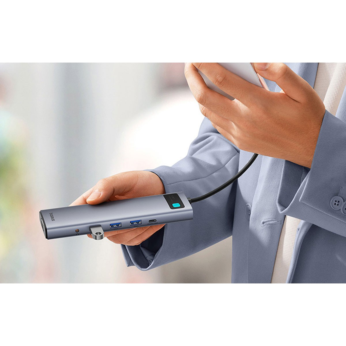 Una mano tiene un hub USB-C grigio con più porte.