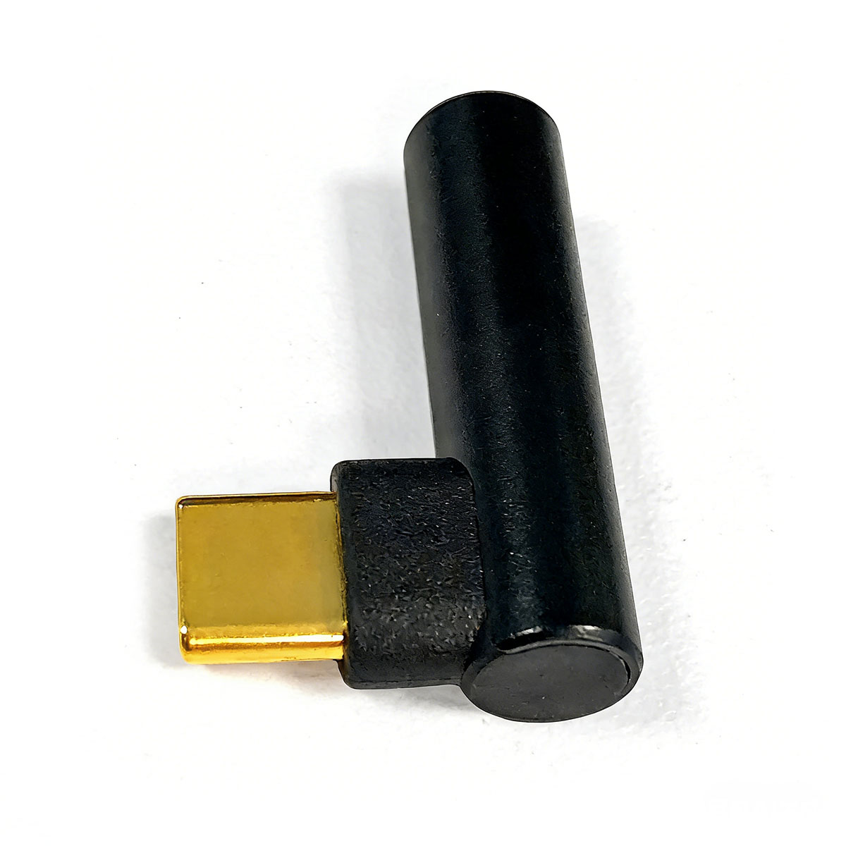 Ein schwarzer Winkeladapter mit goldenem Stecker auf weißem Hintergrund.