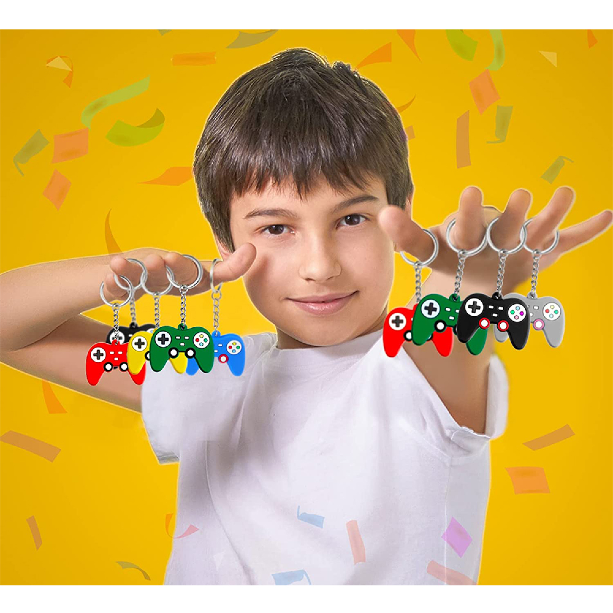 Ein Junge hält Schlüsselanhänger in Form von bunten Gamecontrollern vor einem gelben Hintergrund mit Konfetti.