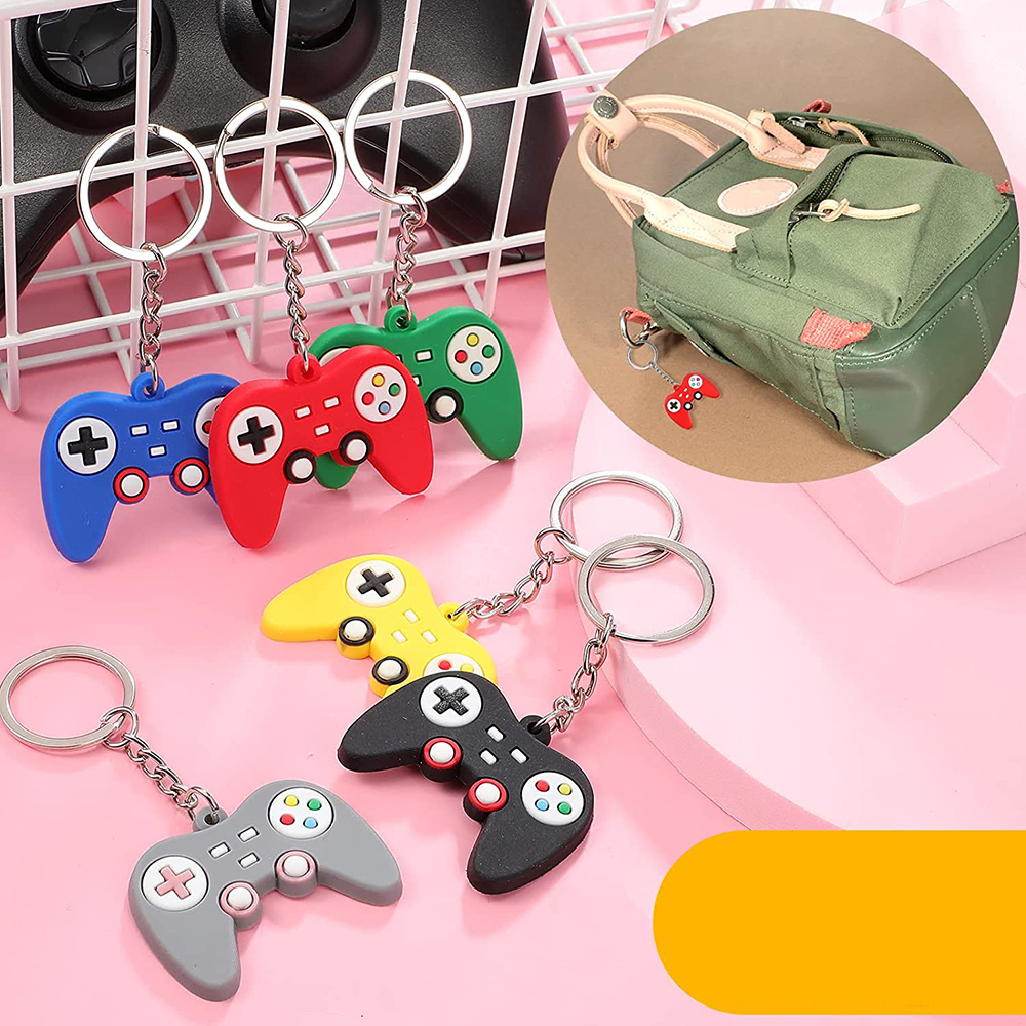 Fünf Schlüsselanhänger in Form von bunten Gamecontrollern liegen auf rosa Untergrund.