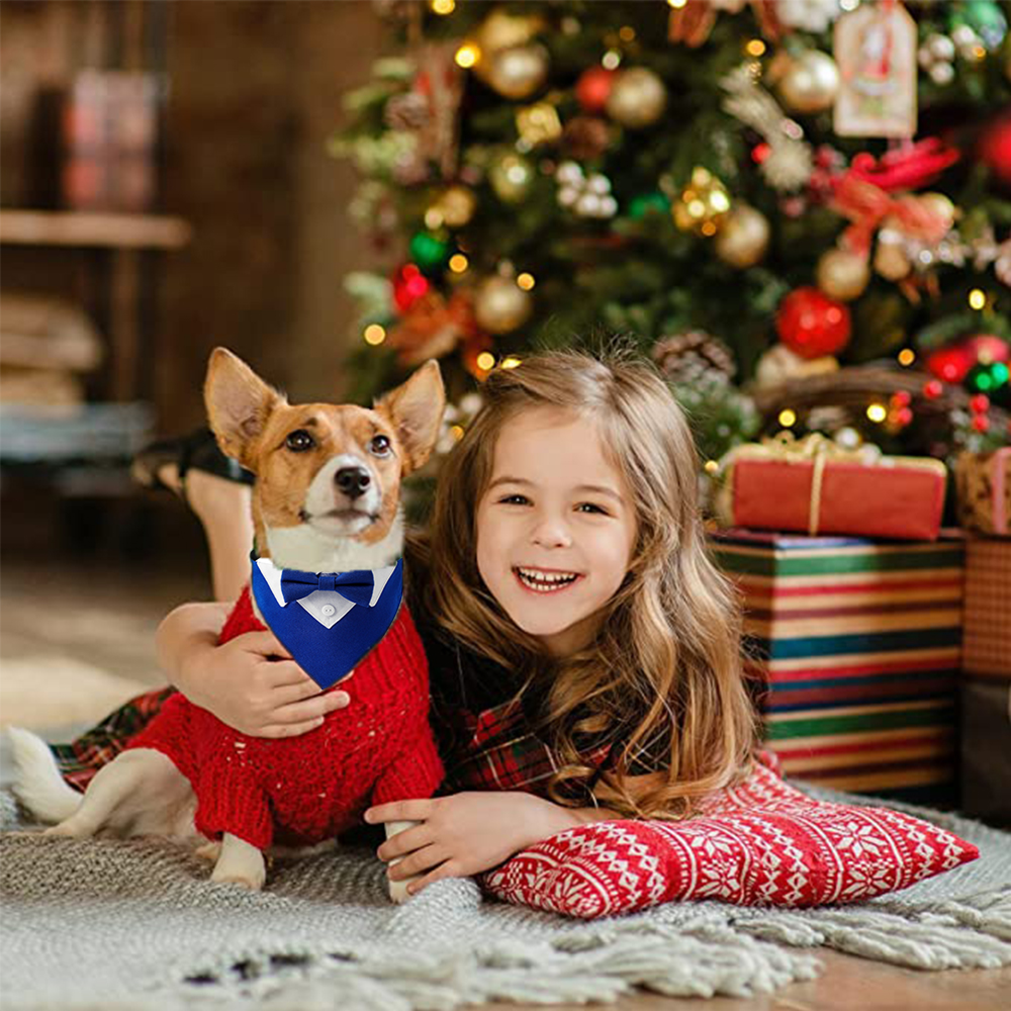 Ein Mädchen und ein Hund liegen vor einem Weihnachtsbaum mit Geschenken.