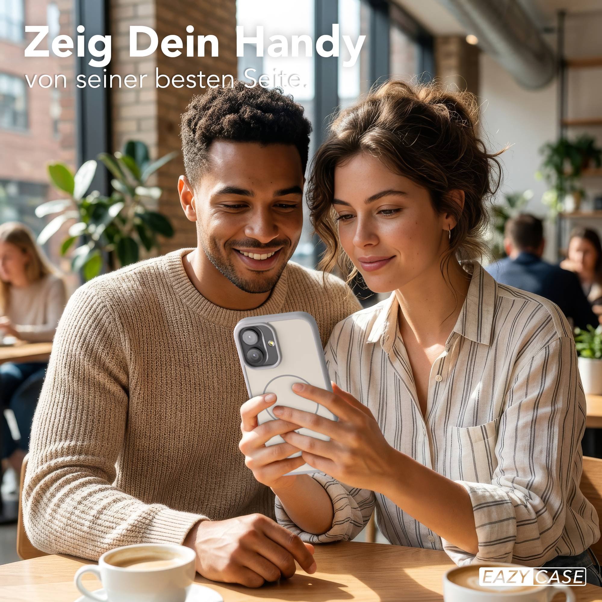 Ein Mann und eine Frau schauen lächelnd auf ein Handy in einem Café.