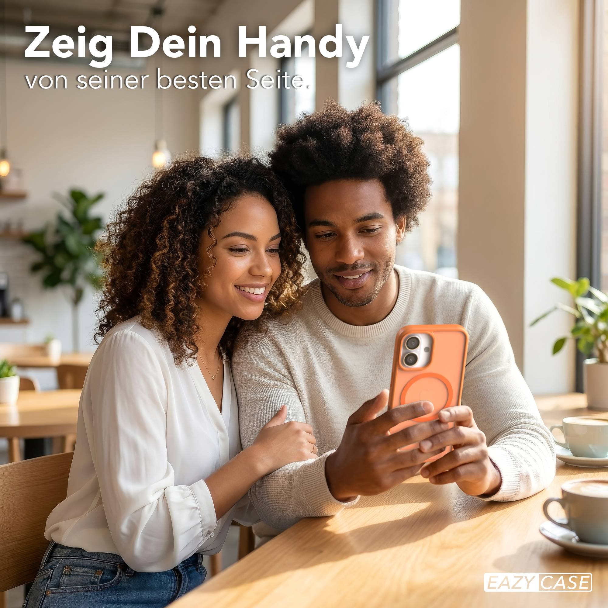 Mann und Frau blicken auf ein Handy in Orangener Hülle auf einem Holztisch.