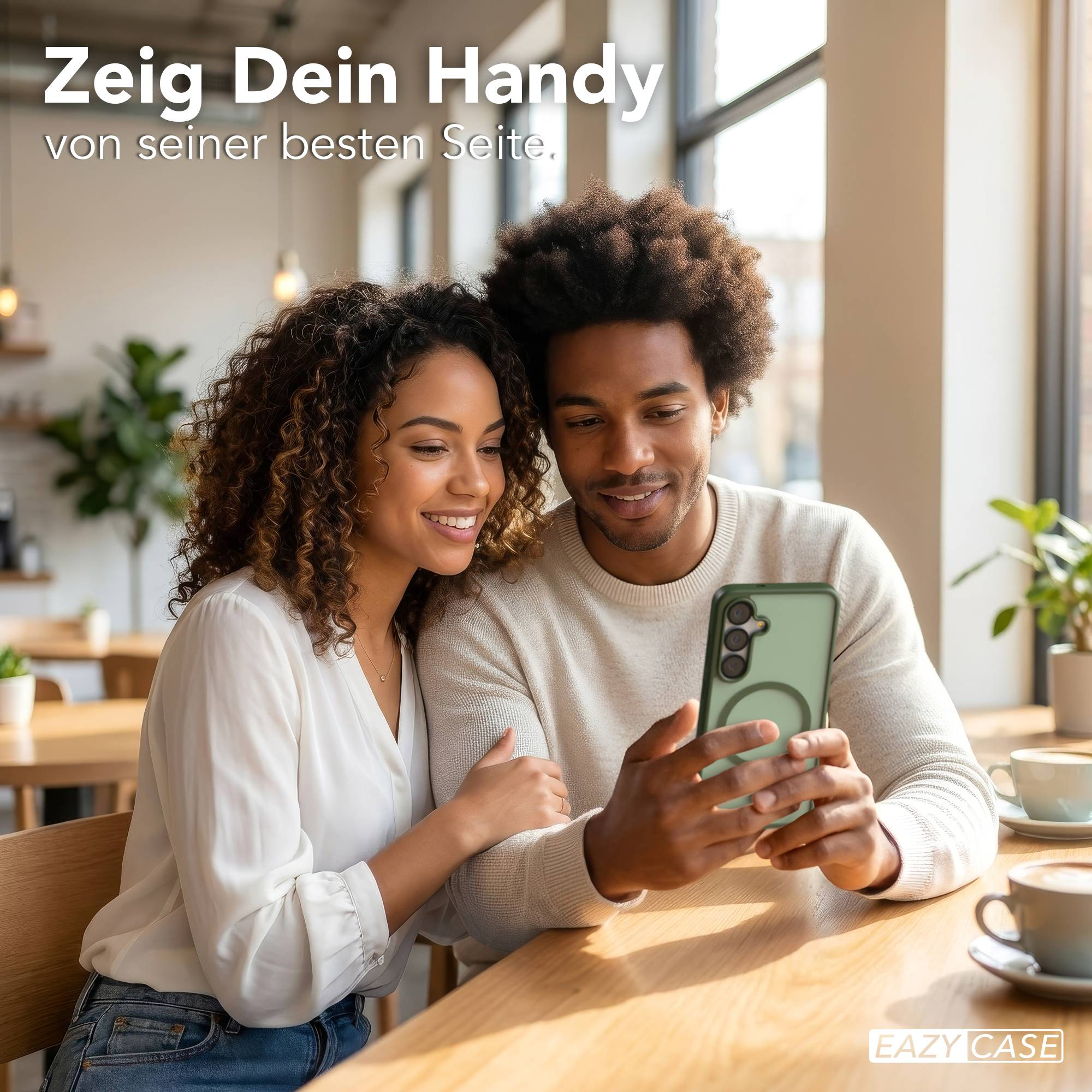 Ein Paar schaut sich ein Handy an, das auf einem Tisch liegt. Kaffeetassen sind daneben.
