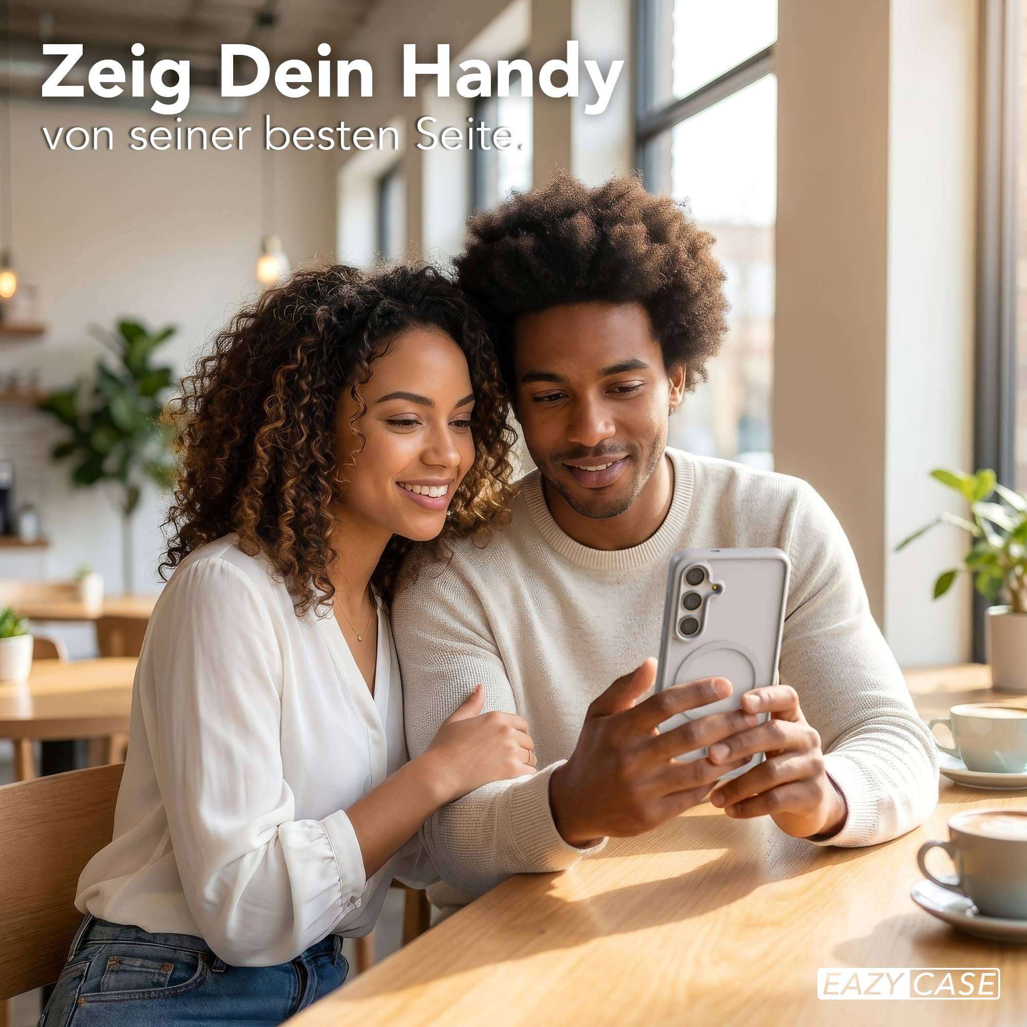 Ein Mann und eine Frau sitzen an einem Holztisch und schauen auf ein Handy.