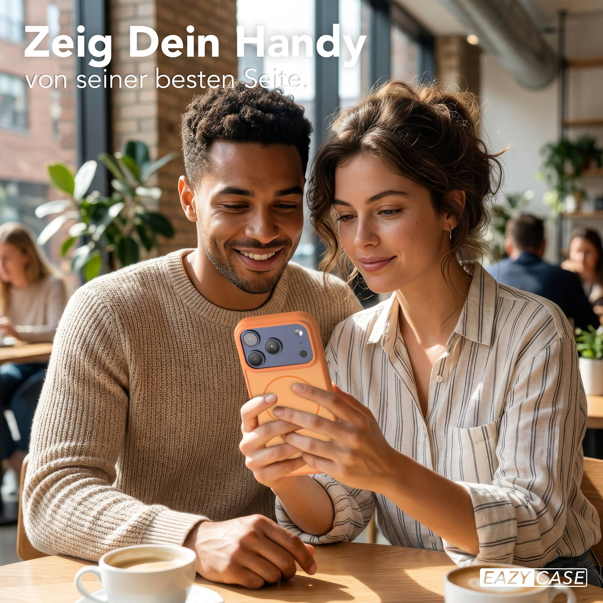 Ein Mann und eine Frau betrachten ein Handy in einer orangefarbenen Hülle in einem Café.