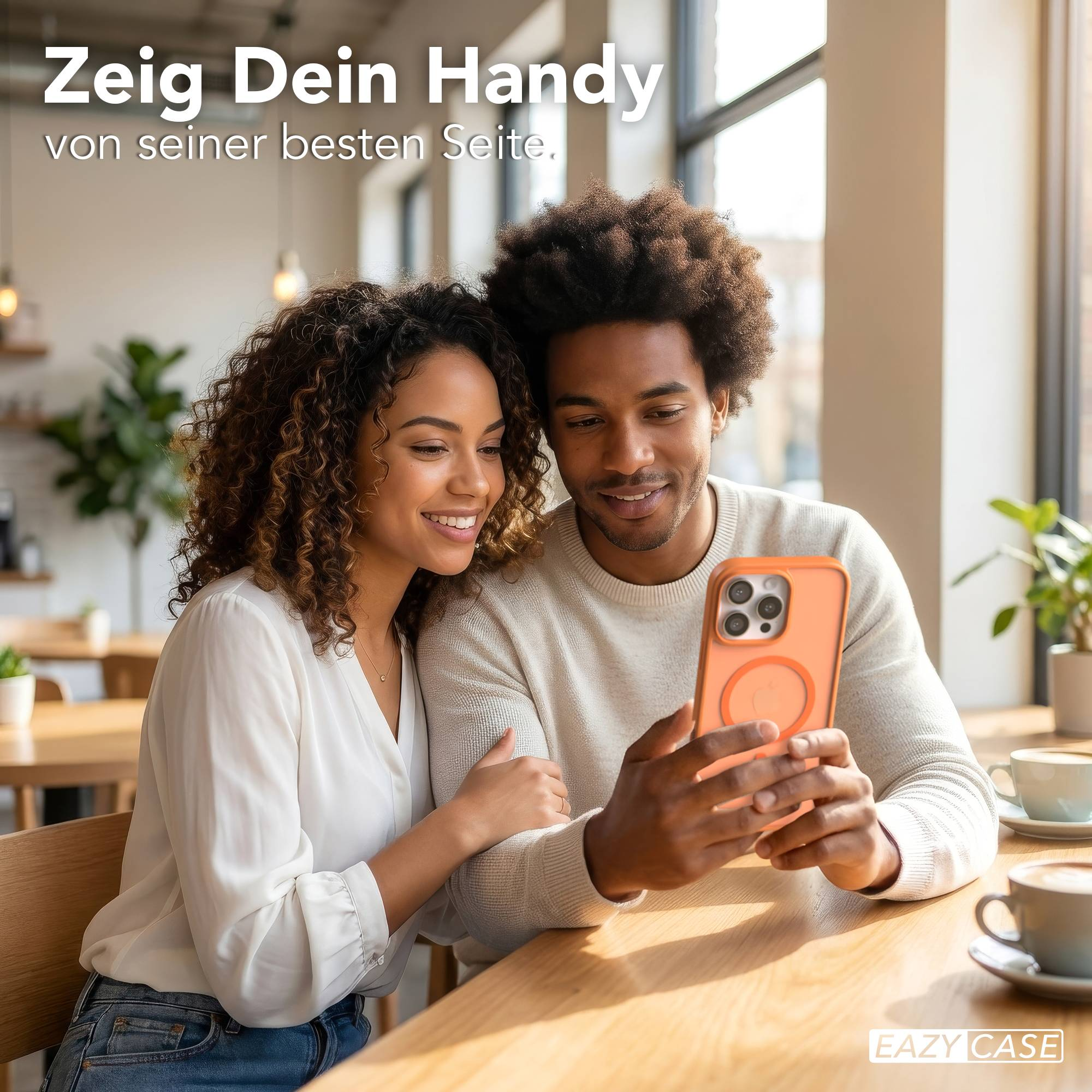 Ein Mann und eine Frau sitzen an einem Holztisch und betrachten ein orangefarbenes Handy.