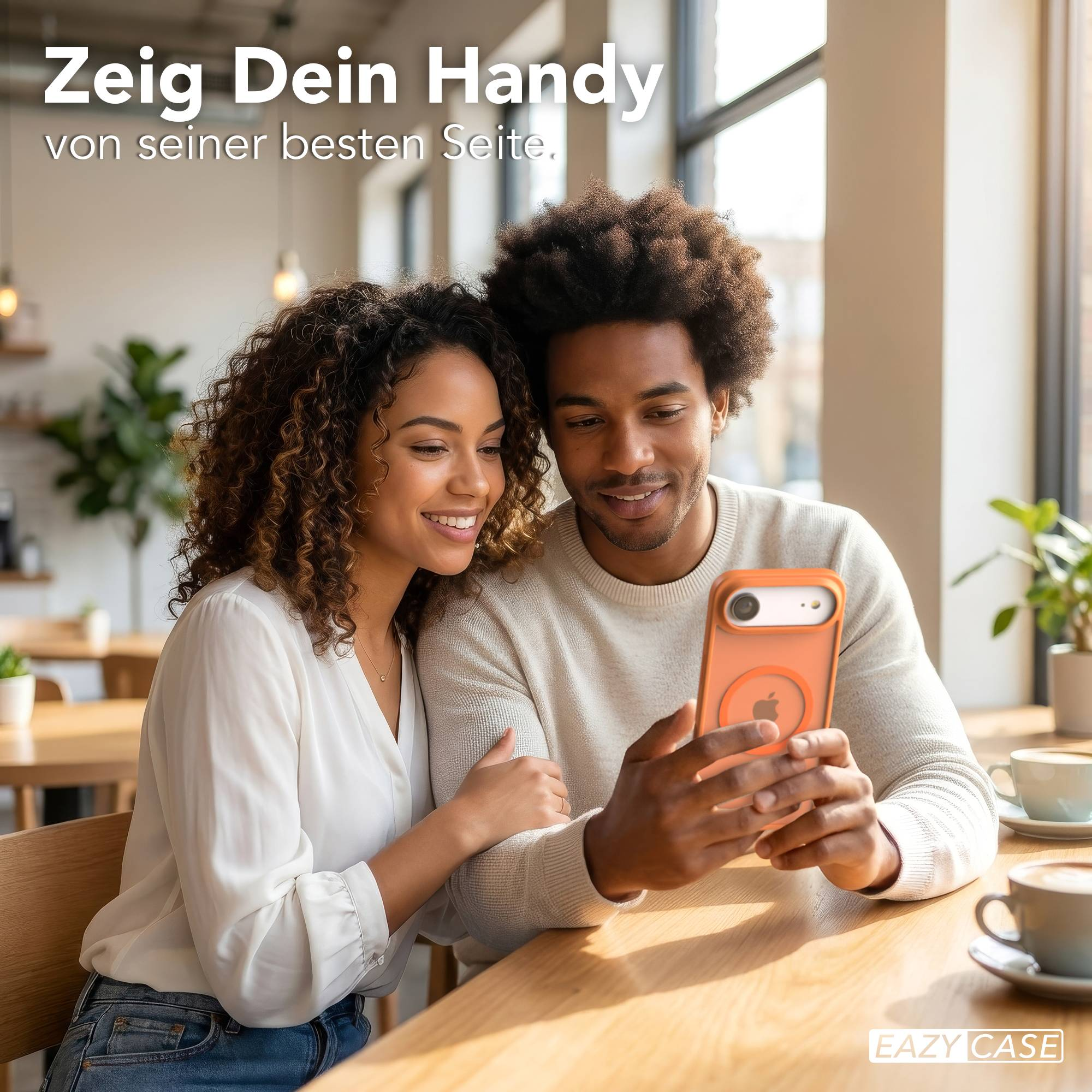 Ein Mann und eine Frau sitzen an einem Holztisch und betrachten ein Handy.