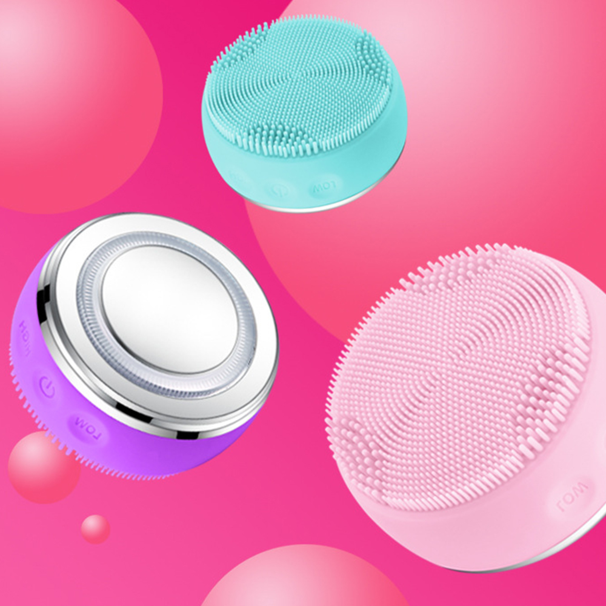 Drei Silikon-Gesichtsreinigungsbürsten in Lila, Türkis und Pink auf pinkem Hintergrund.