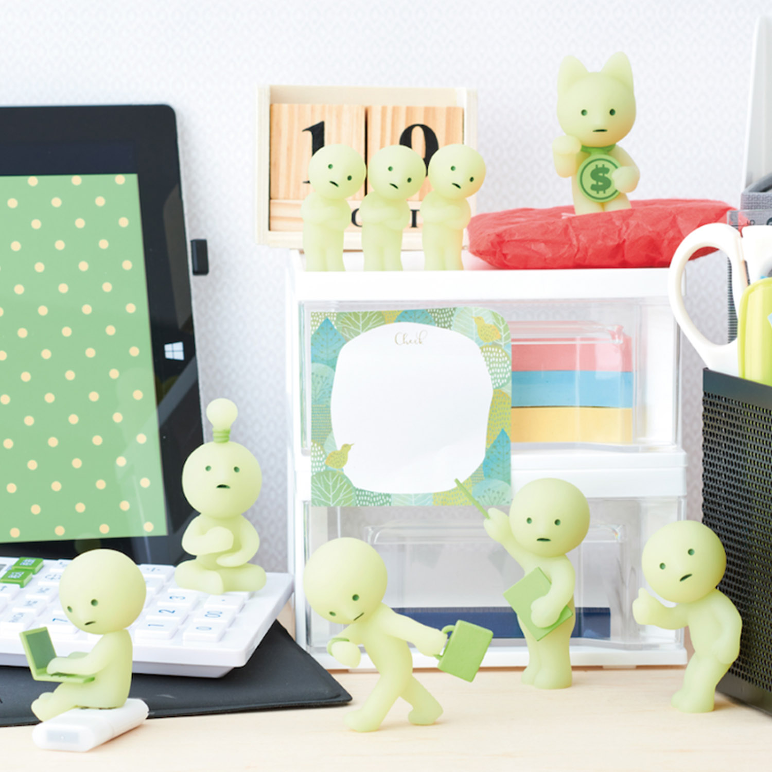 Pastellgrüne Figuren auf einem Schreibtisch, einige mit Laptops, andere mit Büchern.
