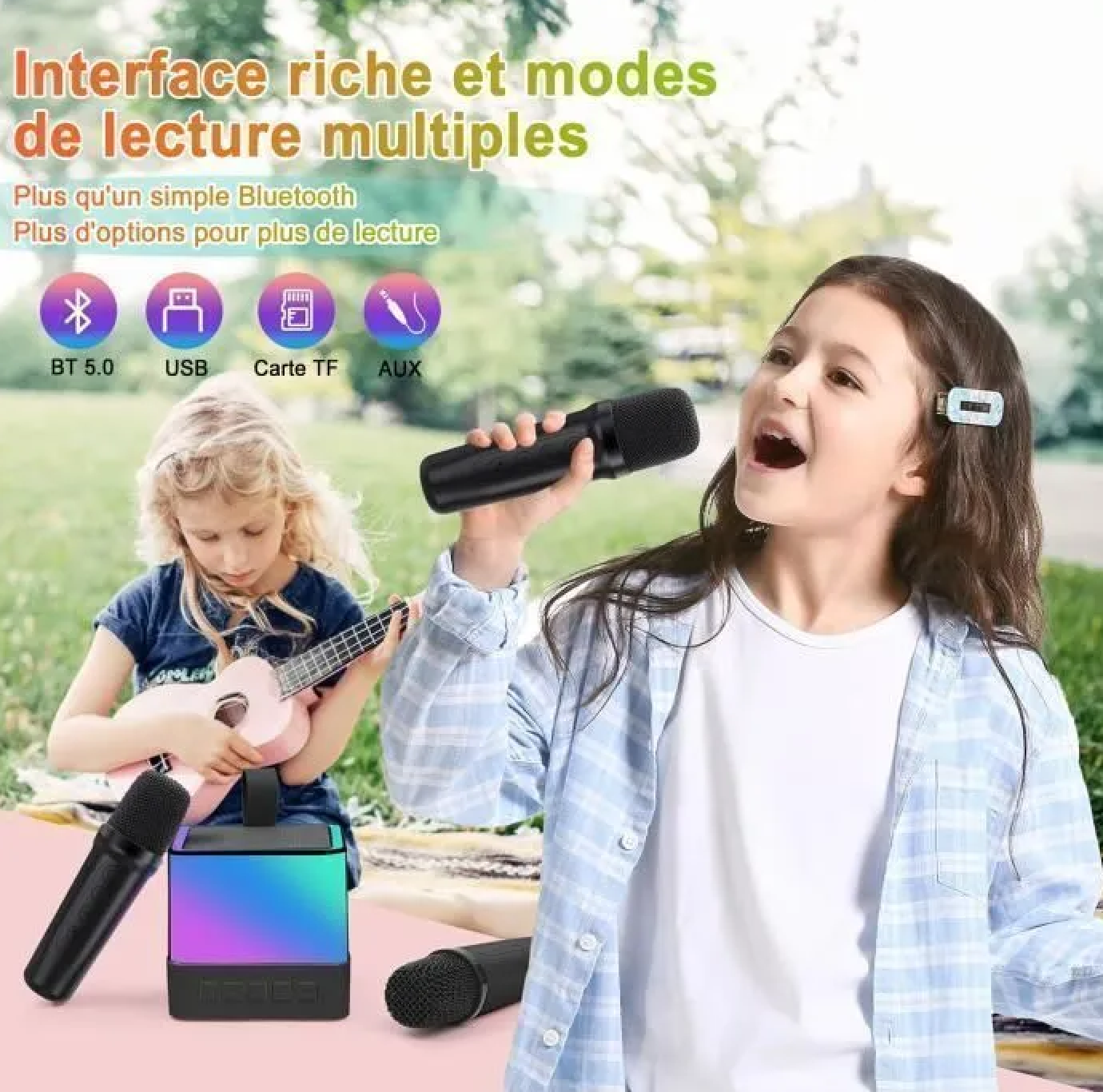 Zwei Mädchen singen und spielen Ukulele mit Mikrofonen und einem bunten Lautsprecher.