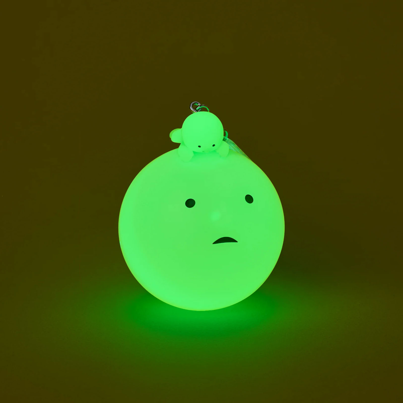 Eine leuchtend grüne Kugel mit einem kleinen grünen Wesen darauf. Sie hat ein Gesicht.